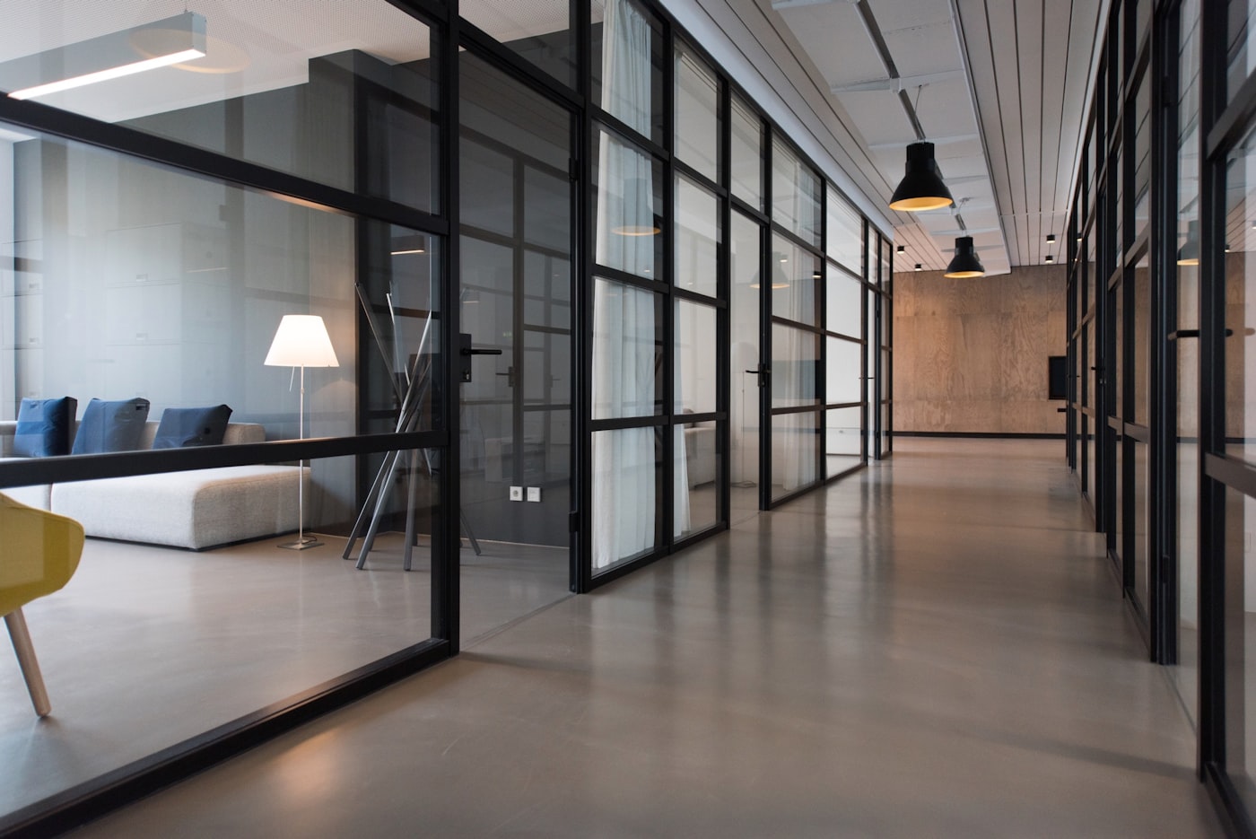 A bright modern office corridor with glass partitions